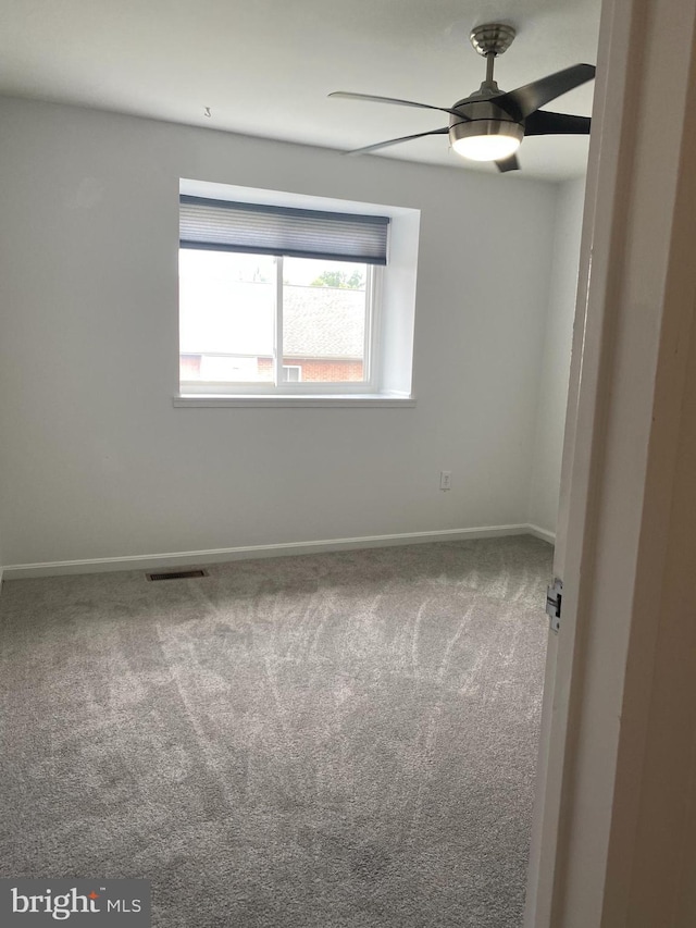 carpeted empty room with visible vents, baseboards, and ceiling fan