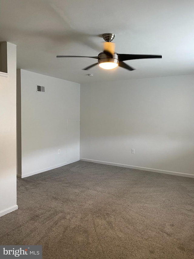 empty room with baseboards, ceiling fan, dark colored carpet, and visible vents
