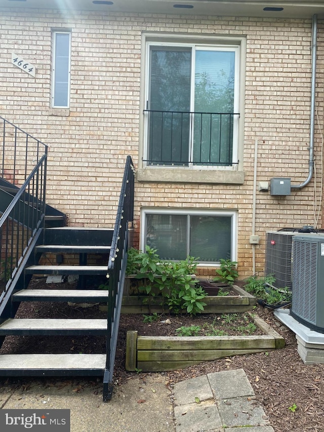 view of exterior entry featuring brick siding and central AC unit