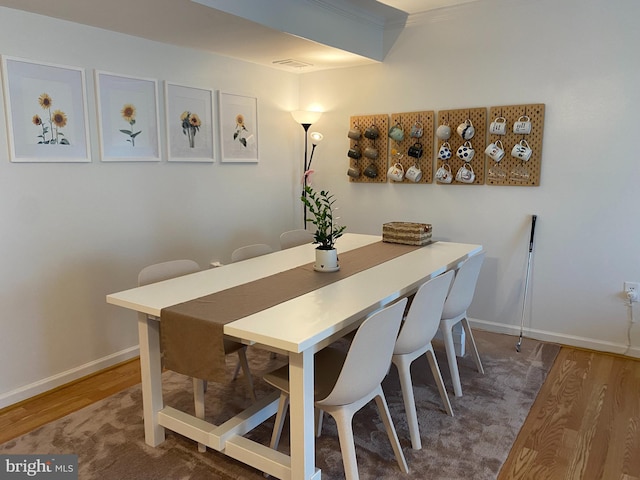 dining area with baseboards, crown molding, wood finished floors, and visible vents