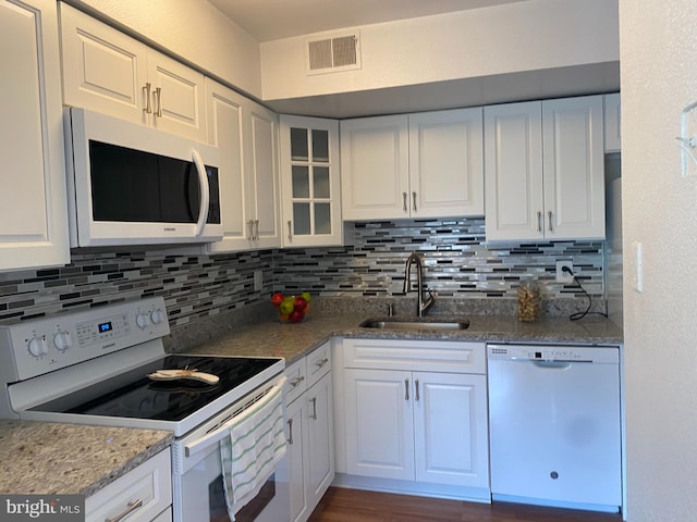 kitchen featuring visible vents, a sink, white cabinetry, and white appliances