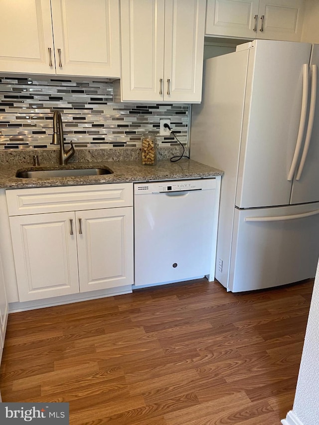 kitchen featuring backsplash, wood finished floors, a sink, white cabinets, and white appliances