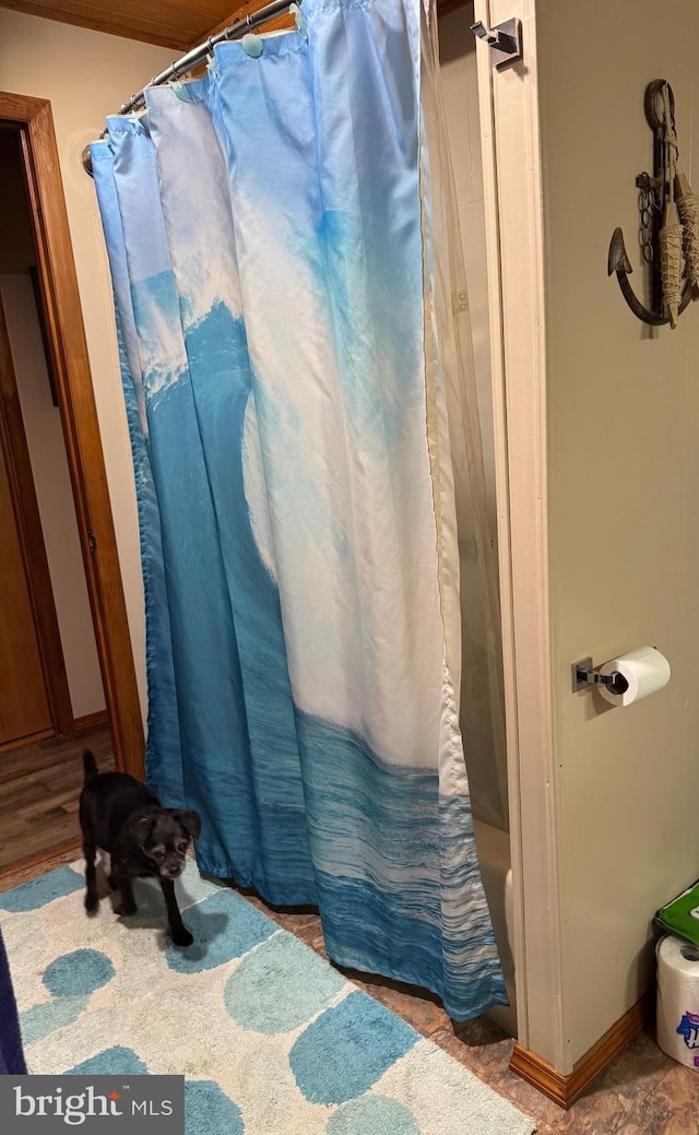 full bath with a shower with curtain and baseboards