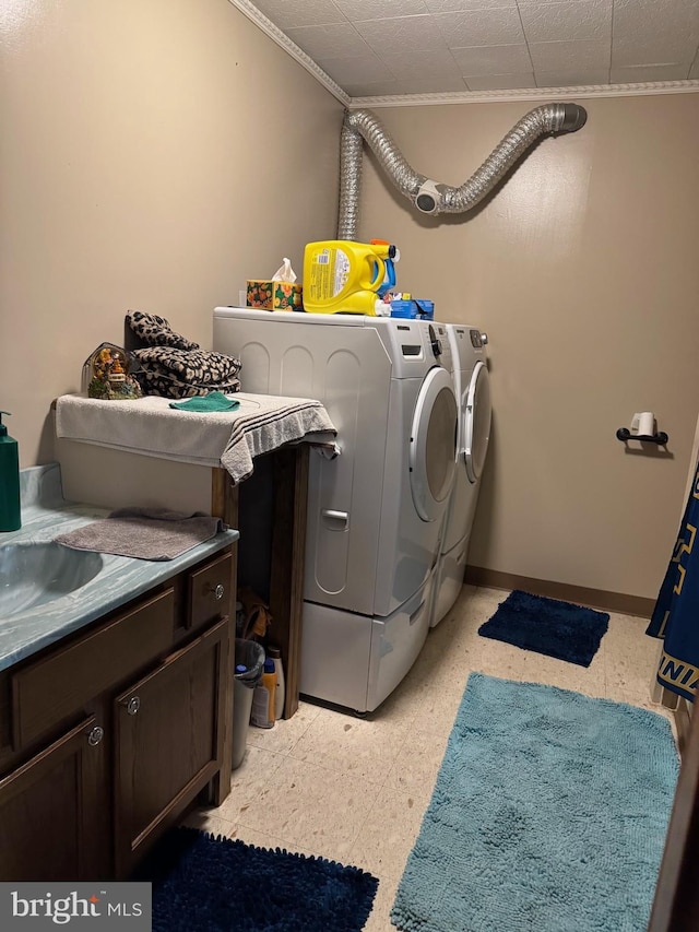 clothes washing area with baseboards, ornamental molding, cabinet space, and washer and clothes dryer