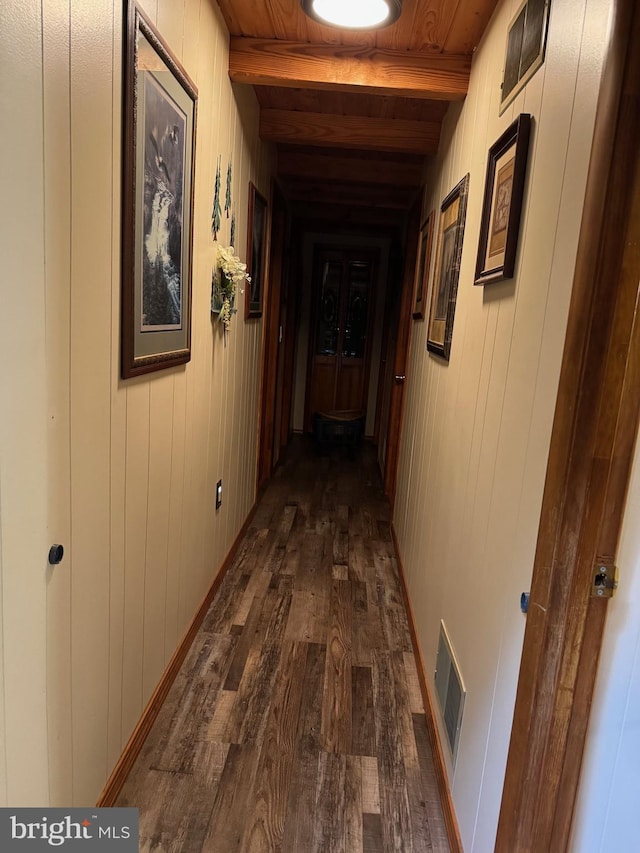 corridor featuring visible vents, dark wood-style flooring, beam ceiling, wooden walls, and wood ceiling