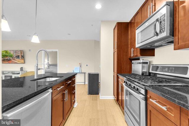 444 W Broad St Unit 407, Falls Church, VA 22046 - kitchen featuring appliances with stainless steel finishes, a sink, dark stone countertops, decorative light fixtures, and brown cabinetry