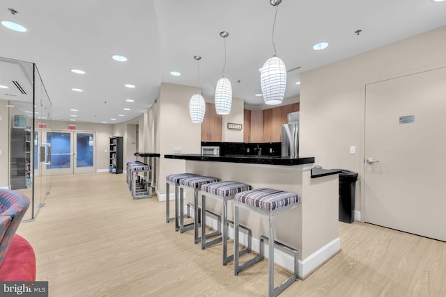 444 W Broad St Unit 407, Falls Church, VA 22046 - kitchen with freestanding refrigerator, light wood-style flooring, a kitchen bar, baseboards, and recessed lighting