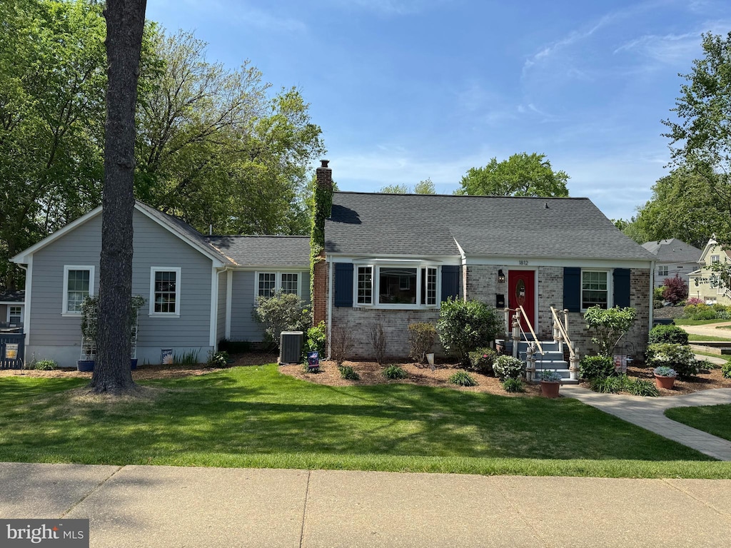 view of front of home featuring a chimney, cooling unit, and a front lawn
