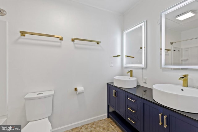 bathroom with baseboards, a sink, double vanity, and toilet