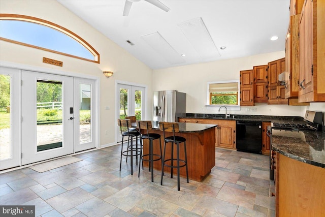 kitchen featuring a breakfast bar area, a kitchen island, visible vents, dishwasher, and stainless steel fridge