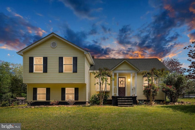 tri-level home featuring a lawn and roof with shingles