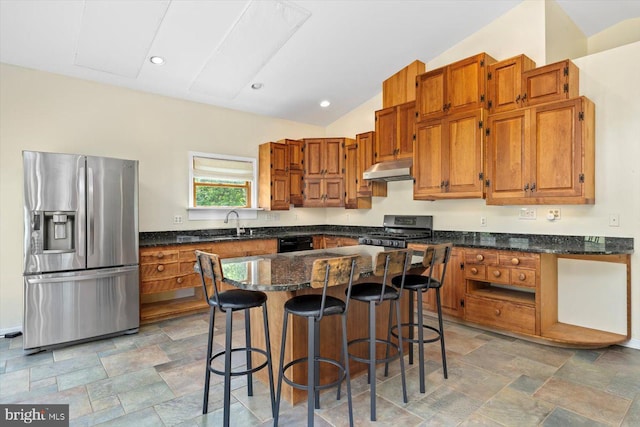 kitchen with brown cabinetry, stone finish floor, and stainless steel appliances