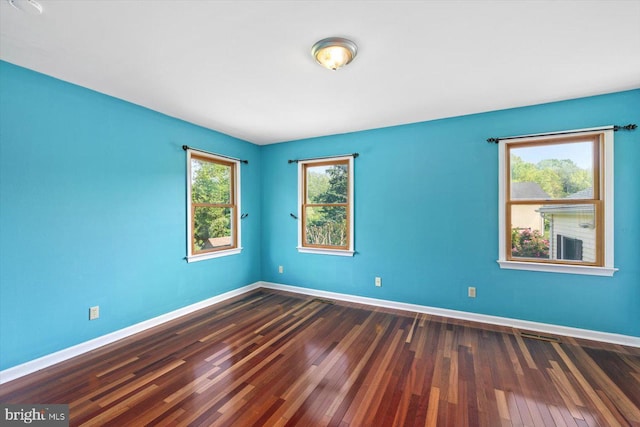 unfurnished room featuring baseboards and dark wood finished floors