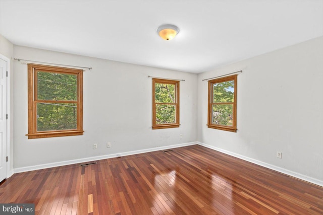 spare room with baseboards, visible vents, and hardwood / wood-style flooring
