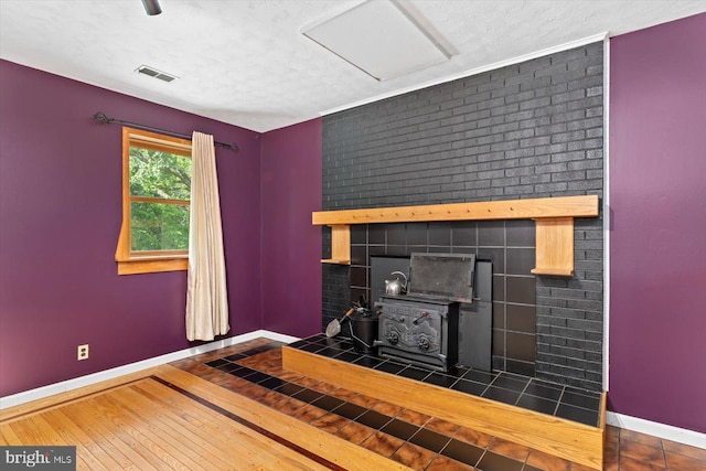 living room with baseboards, a wood stove, visible vents, and hardwood / wood-style flooring