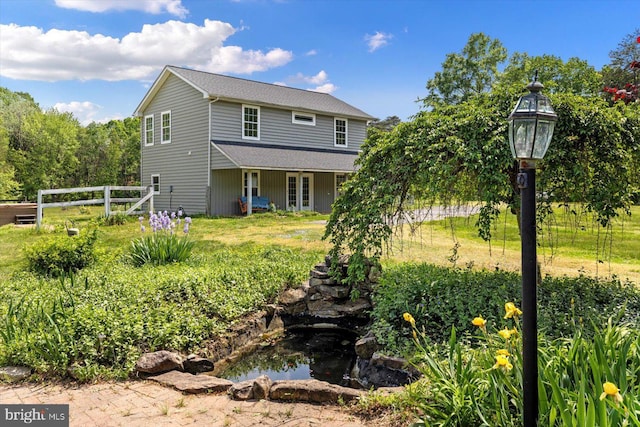 back of house with a small pond and fence