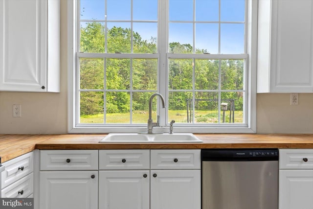 kitchen with butcher block countertops, a sink, white cabinetry, and stainless steel dishwasher