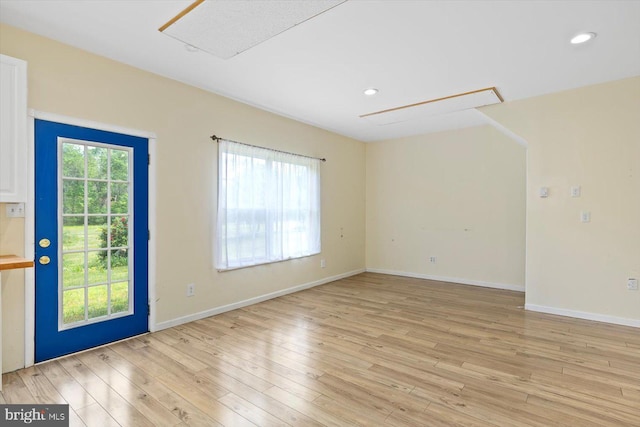 spare room featuring recessed lighting, baseboards, attic access, and light wood finished floors