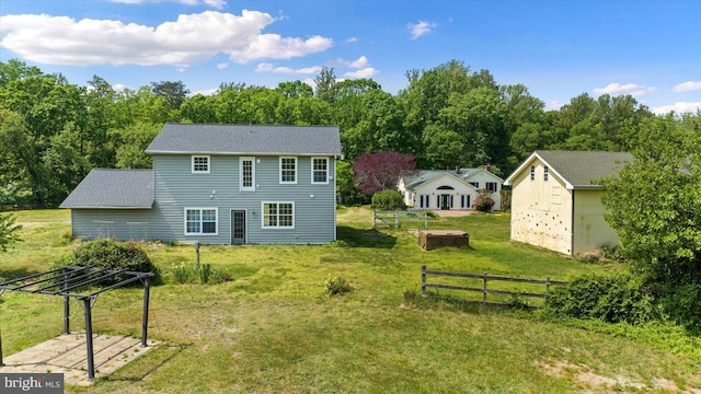 rear view of property with a lawn, fence, a storage shed, and an outdoor structure