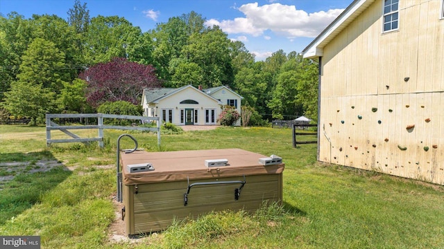entry to storm shelter featuring a lawn, an outdoor structure, a jacuzzi, and fence