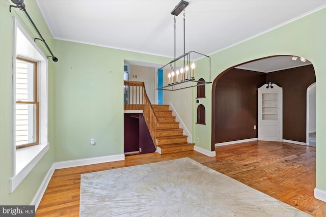 unfurnished dining area with arched walkways, a wealth of natural light, and wood finished floors