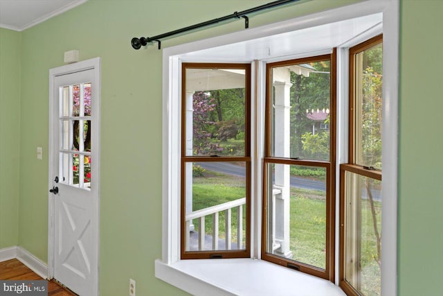 doorway to outside with crown molding, baseboards, and wood finished floors