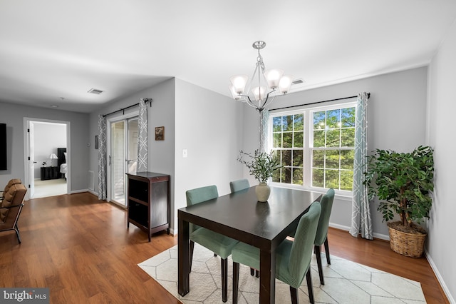 dining area featuring baseboards, wood finished floors, a chandelier, and visible vents