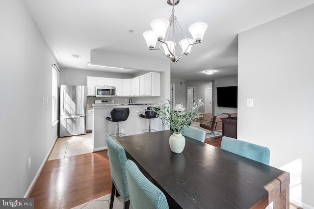 dining area with baseboards, a notable chandelier, visible vents, and light wood-style floors