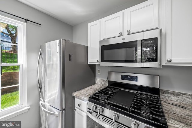 kitchen featuring appliances with stainless steel finishes, plenty of natural light, and white cabinets