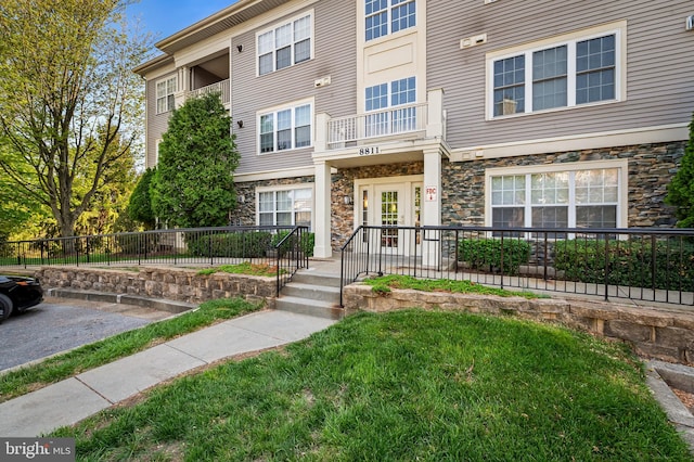 view of property with a front yard, fence, and stone siding