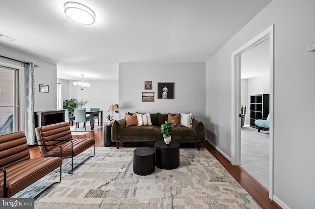 living area with baseboards, wood finished floors, a notable chandelier, and visible vents
