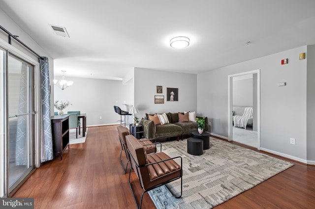 living room featuring visible vents, baseboards, wood finished floors, and a chandelier
