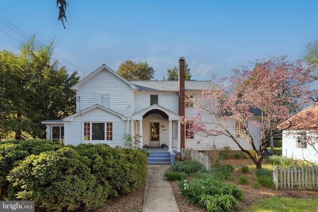 traditional-style home featuring fence and a chimney