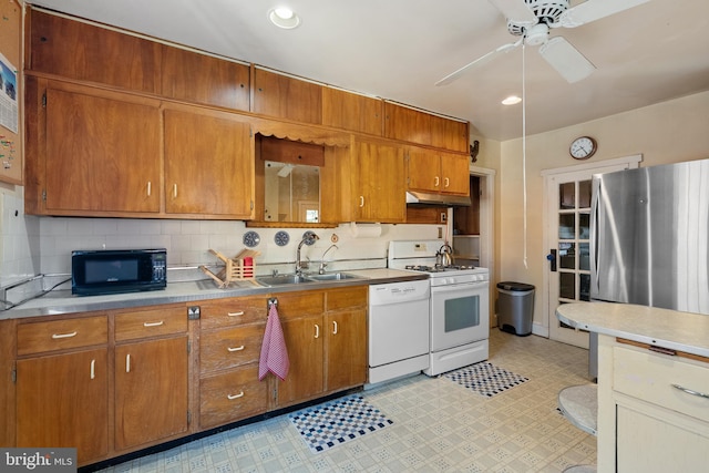 kitchen with brown cabinetry, white appliances, ceiling fan, under cabinet range hood, and a sink