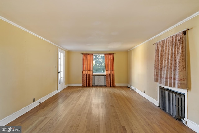unfurnished living room with baseboards, ornamental molding, radiator heating unit, and wood finished floors