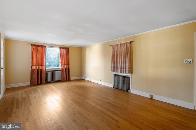 unfurnished living room with baseboards, ornamental molding, radiator heating unit, and light wood-style flooring