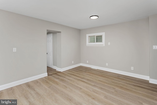 spare room with baseboards and wood finished floors