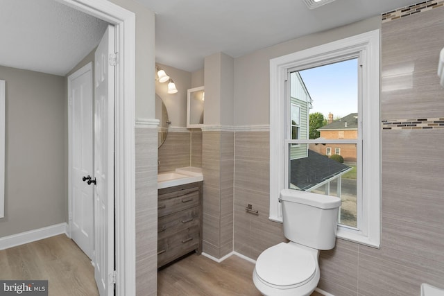 bathroom featuring tile walls, vanity, toilet, and wood finished floors