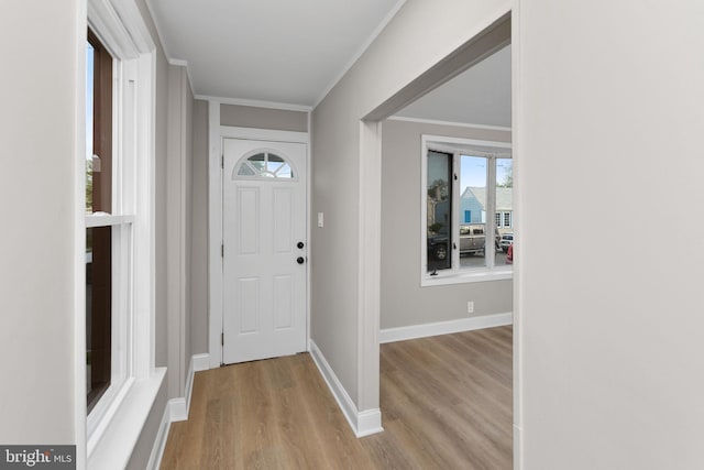 foyer with crown molding, baseboards, and wood finished floors