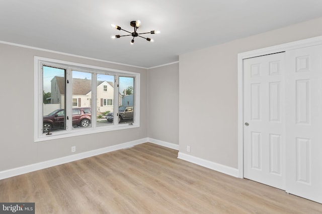interior space featuring baseboards, light wood-style flooring, crown molding, and a chandelier