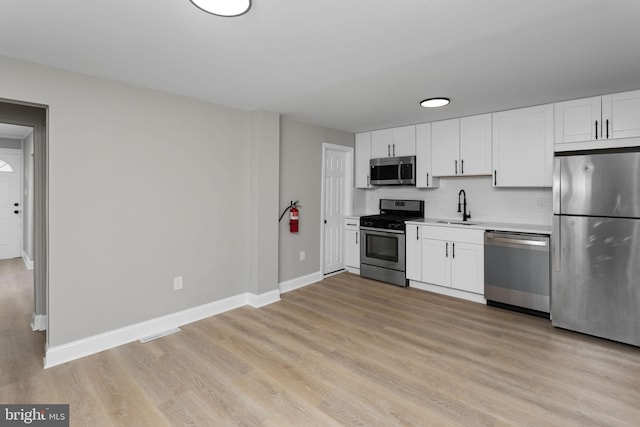 kitchen featuring baseboards, a sink, white cabinets, and stainless steel appliances
