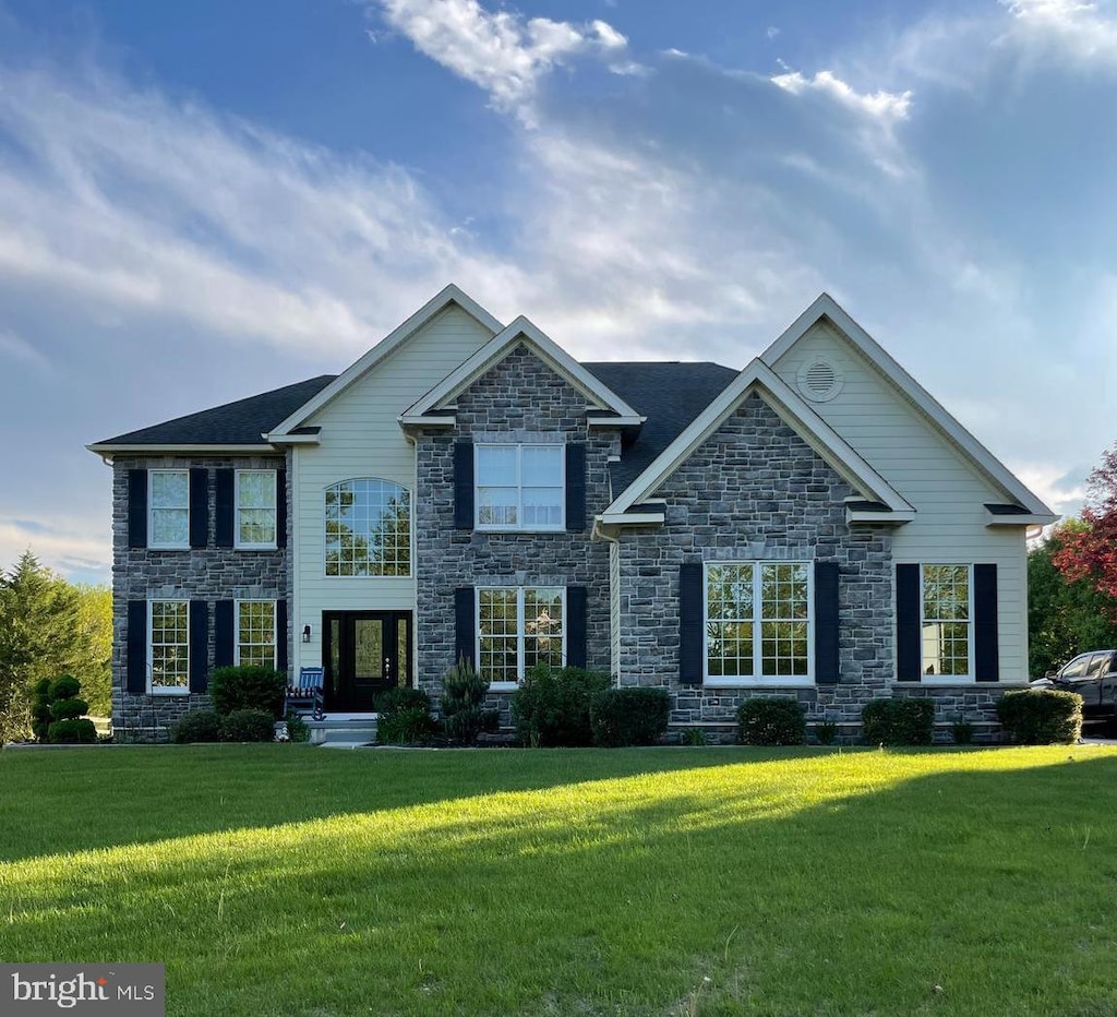 view of front of property with a front yard and stone siding
