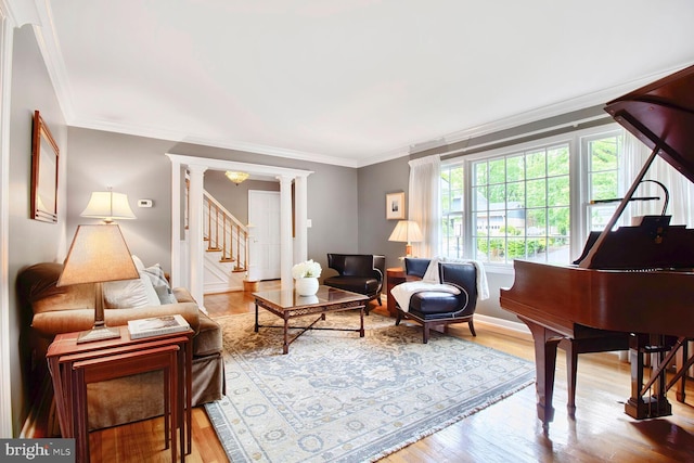 living room featuring baseboards, ornamental molding, decorative columns, wood finished floors, and stairway