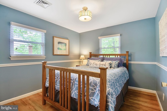 bedroom featuring baseboards, visible vents, and wood finished floors