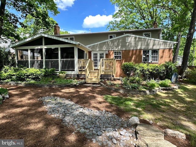 exterior space featuring a sunroom, a wooden deck, a chimney, and brick siding
