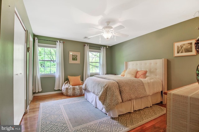 bedroom with a ceiling fan, baseboards, visible vents, and wood finished floors