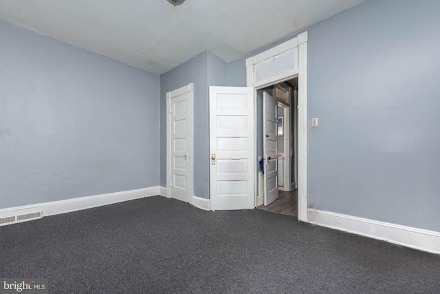 unfurnished bedroom featuring dark colored carpet, baseboards, and visible vents
