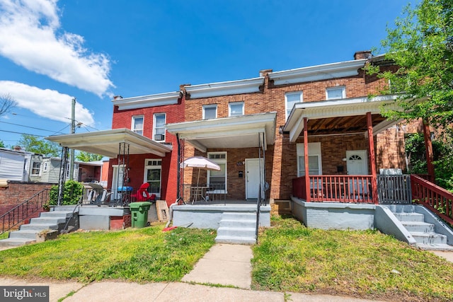 townhome / multi-family property with a porch and brick siding