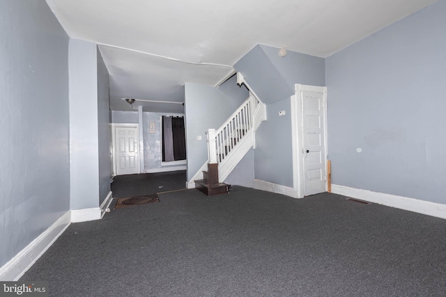 interior space featuring carpet flooring, baseboards, visible vents, and stairway