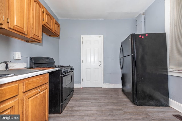 kitchen with visible vents, baseboards, light wood-type flooring, light countertops, and black appliances